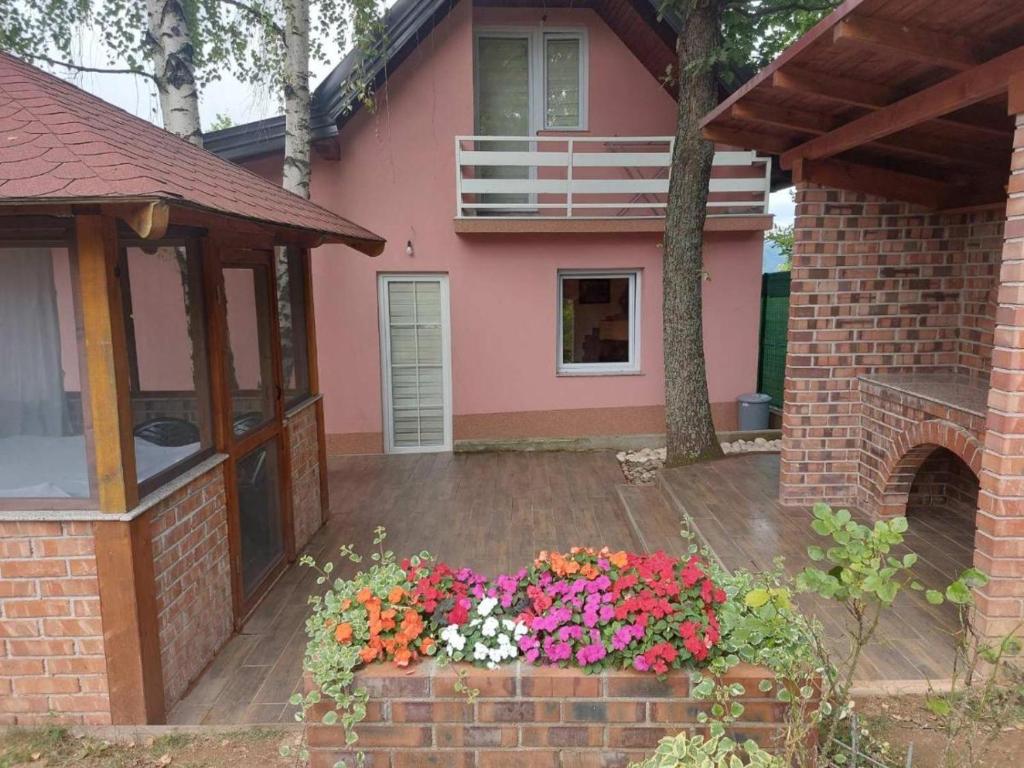 Une maison rose avec un bouquet de fleurs devant elle dans l'établissement Vikendica Ahatovići 2, à Sarajevo