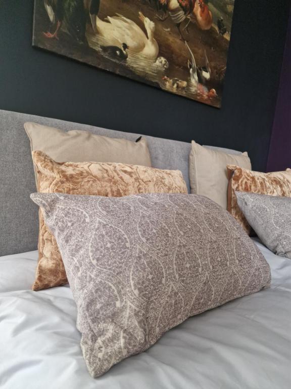 a bed with pillows and a painting on the wall at Our House in Breskens