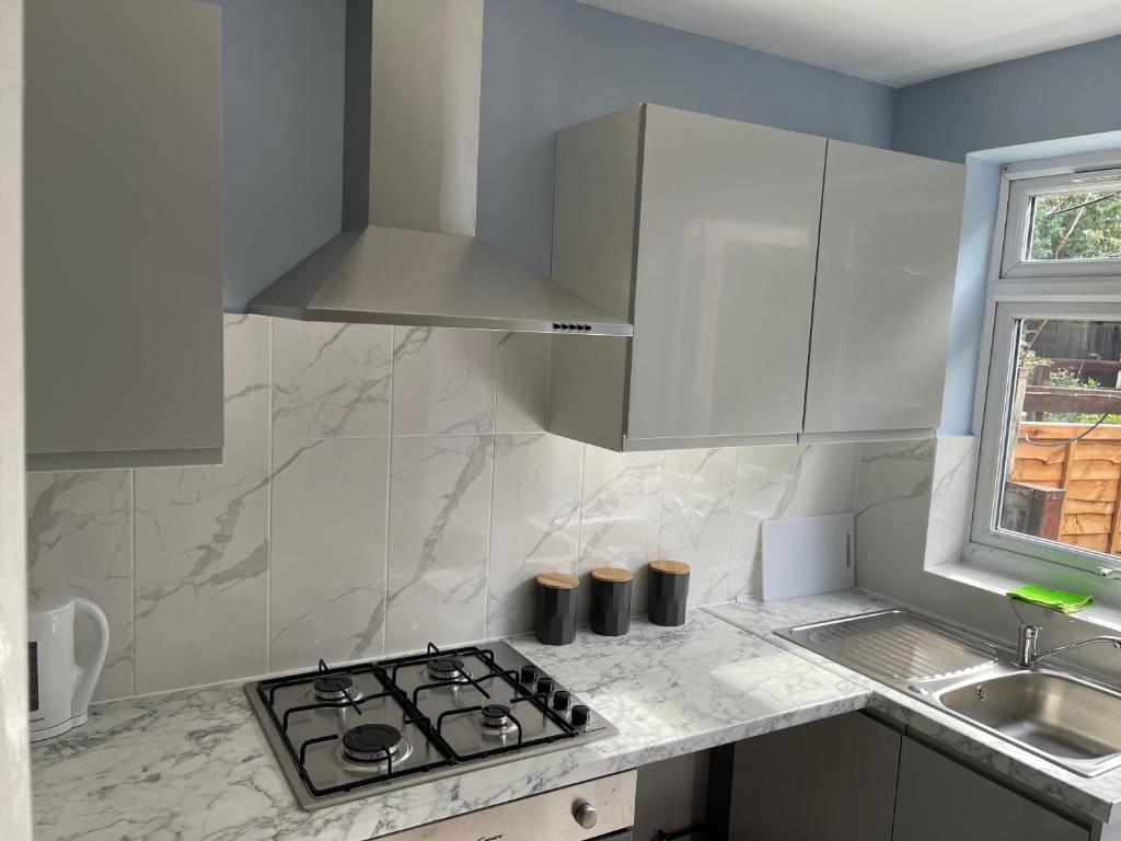 a white kitchen with a stove and a sink at Entire Lovely 2 bedroom apartment with private garden & free street parking in London