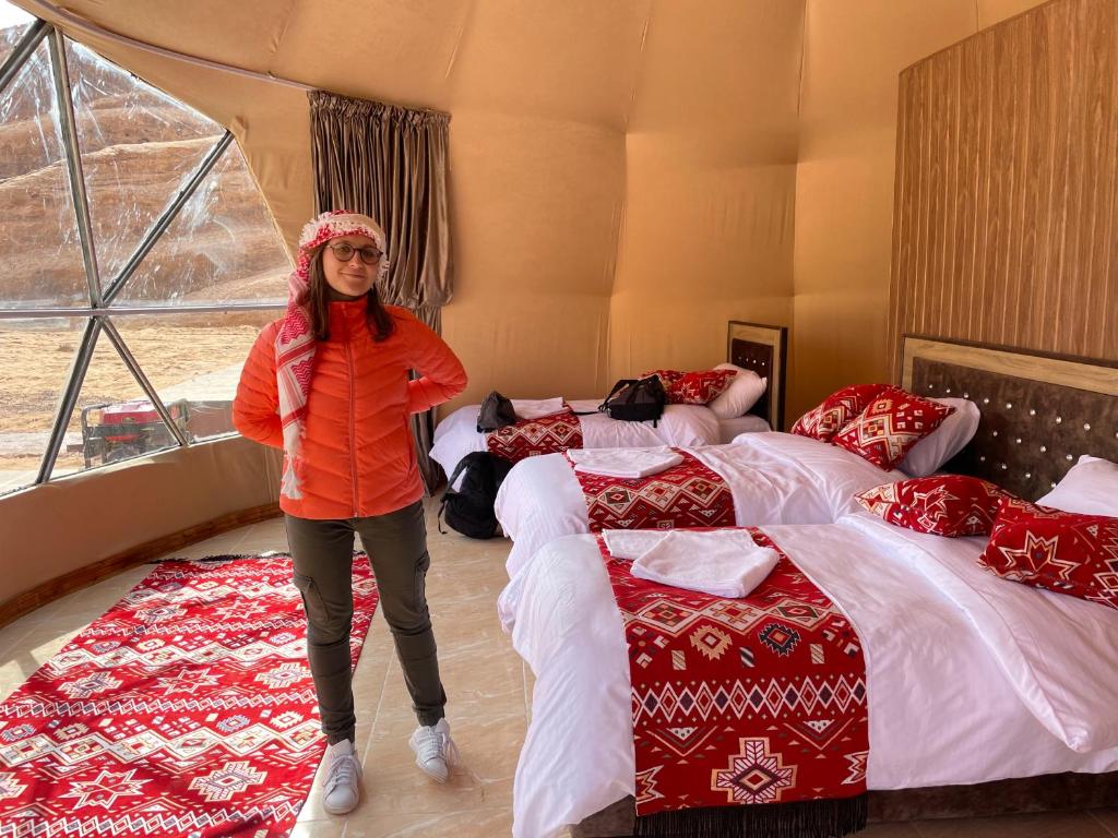 una donna in piedi in una stanza con due letti di Zarb Desert Camp a Wadi Rum