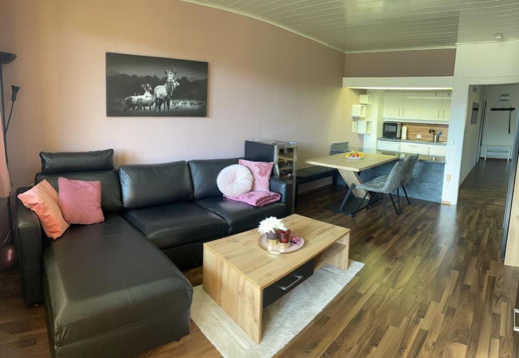 a living room with a black couch and a table at Weinapartment St. Urban in Sankt Urban