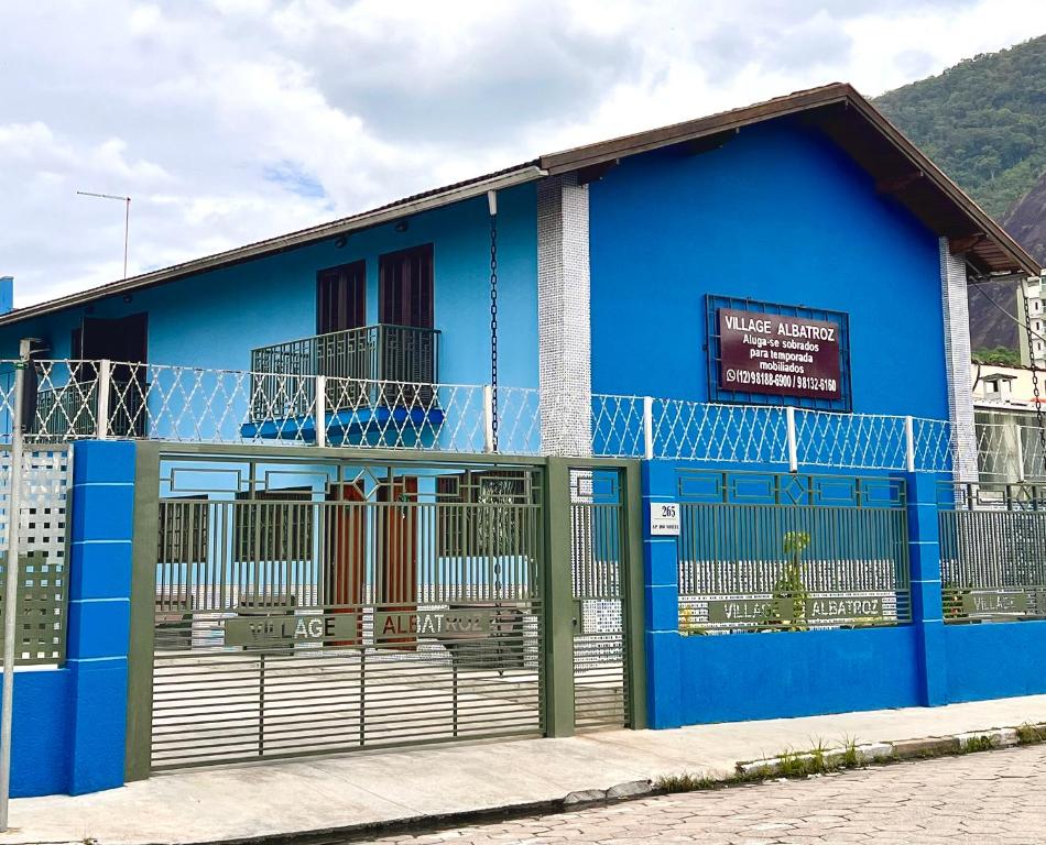 a blue building with a gate in front of it at Residencial Albatroz in Caraguatatuba