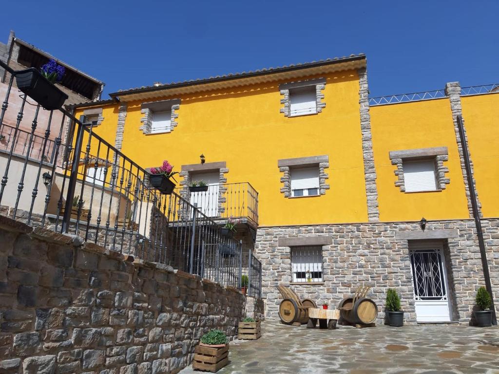 um grande edifício amarelo com uma parede de pedra em Apartamentos Rurales Parajes de Piedra em Ibdes