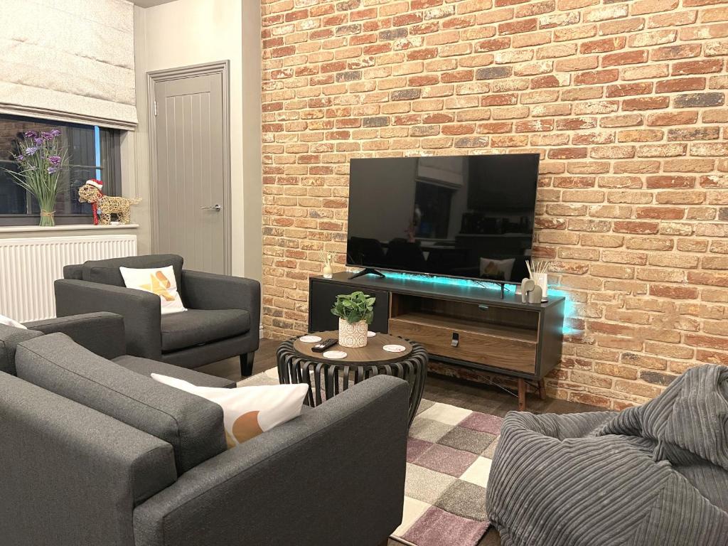 a living room with two couches and a brick wall at Brand New SILVER FORGE - Charming Two Bedroom Apartment - City Centre - Lux Apartment in Birmingham