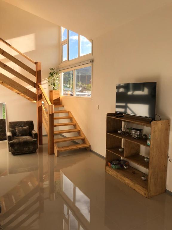 een woonkamer met een trap en een televisie bij Casa Grande, Alojamiento "BSA" in Cochrane