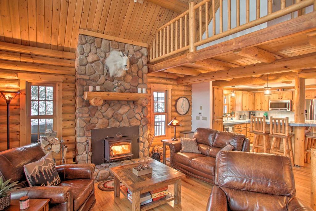 uma sala de estar com mobiliário de couro e uma lareira de pedra em Rustic Gotham Bay Cabin on Lake Coeur dAlene em Harrison