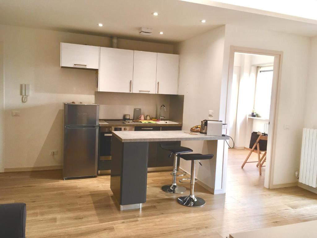 a kitchen with white cabinets and a kitchen island with stools at Appartamento con due camere da letto e free park in Verona