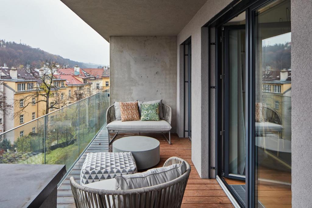 balcón con sofá, mesa y sillas en Designer Apartments in Smíchov by Prague Days, en Praga