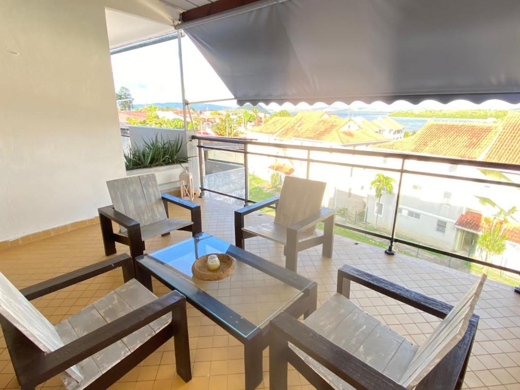 a living room with a glass table and chairs at Grand appartement composé de 2 terrasses avec vue sur mer in Les Trois-Îlets