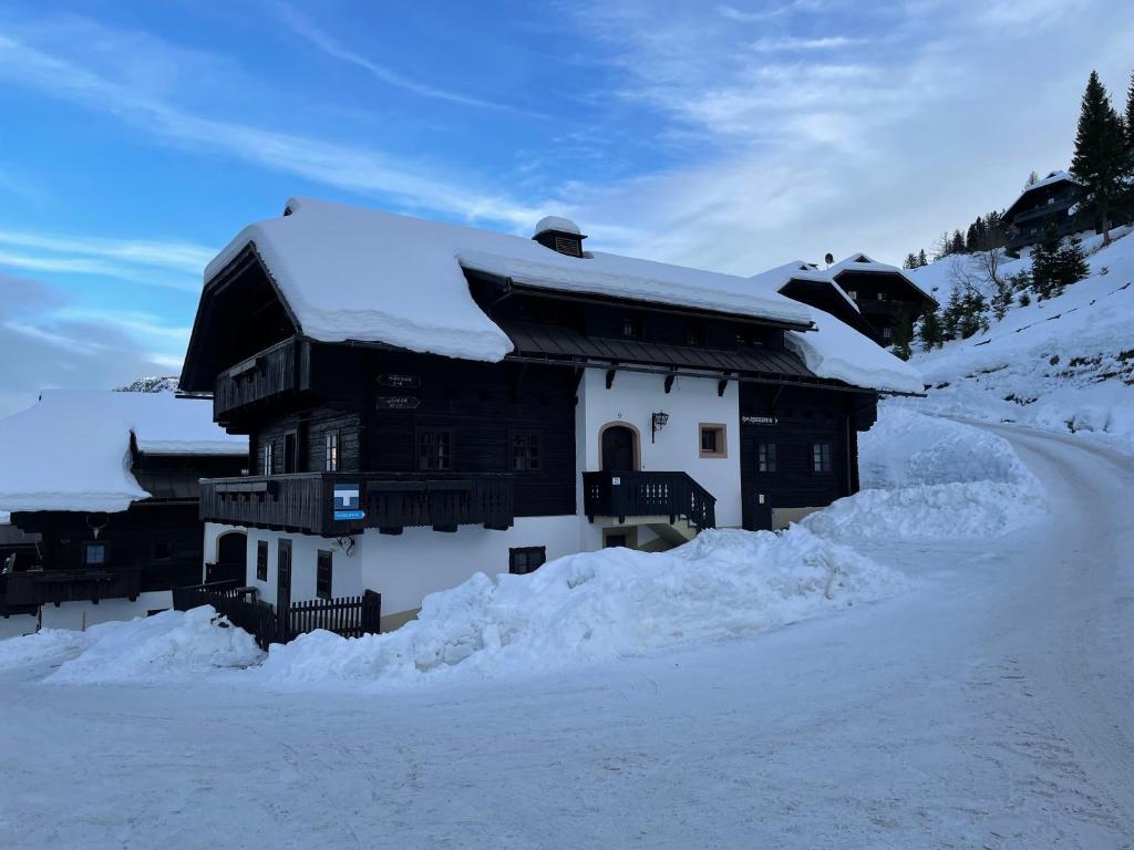 een met sneeuw bedekt gebouw met een met sneeuw bedekt dak bij Appartement Sonnleitn in Sonnenalpe Nassfeld