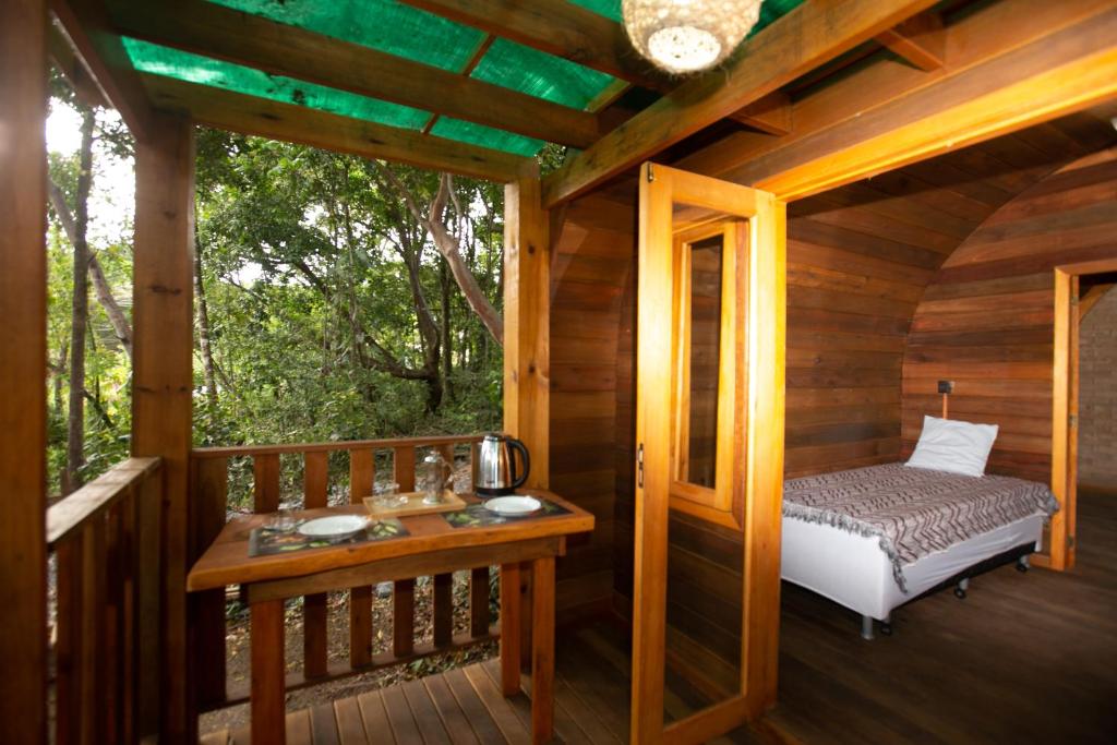 eine Veranda einer Holzhütte mit einem Bett in der Unterkunft ALQUIMIA Hospedaria in Praia do Forte
