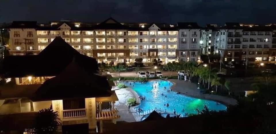 a view of a hotel with a pool at night at Cozy 2BR with FREE Pool beside SM City Mall in Davao City