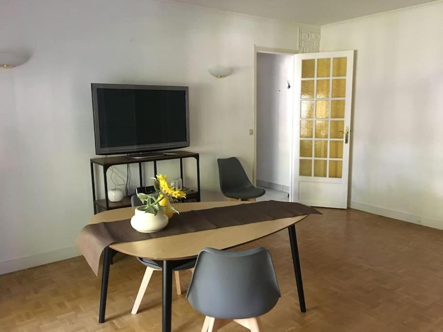 un salon avec une télévision, une table et des chaises dans l'établissement Superbe appartement, résidence familiale, parking, à Chevilly-Larue