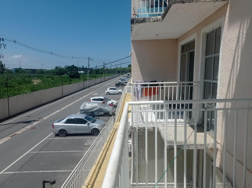 un balcón de un edificio con coches aparcados en la calle en Apto Mod life, en Campos dos Goytacazes