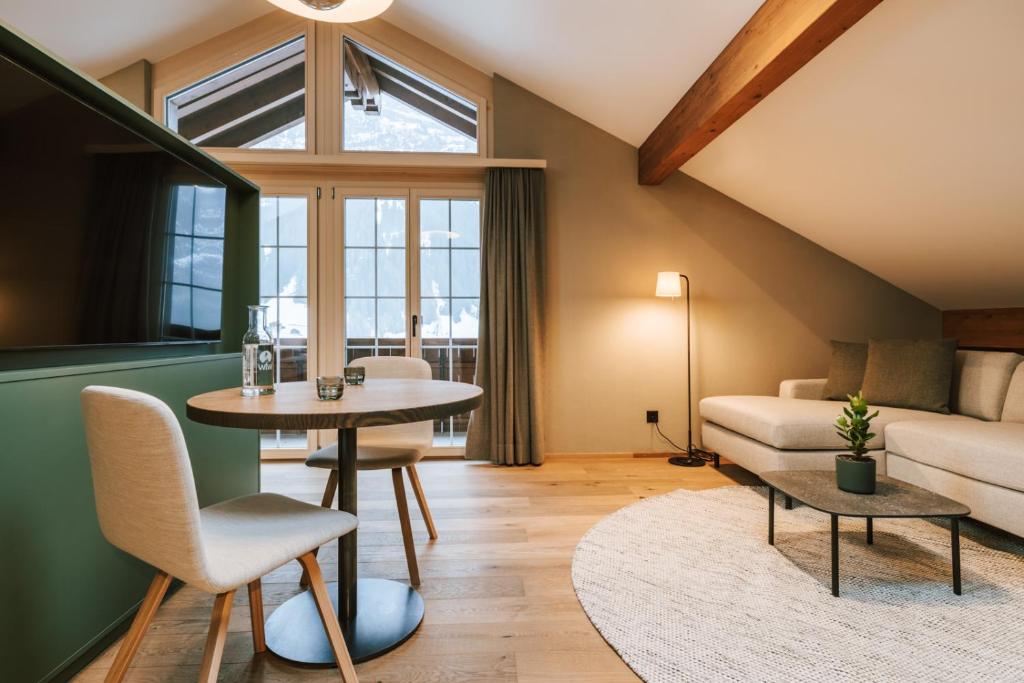 a living room with a table and a couch at Hotel Fiescherblick in Grindelwald