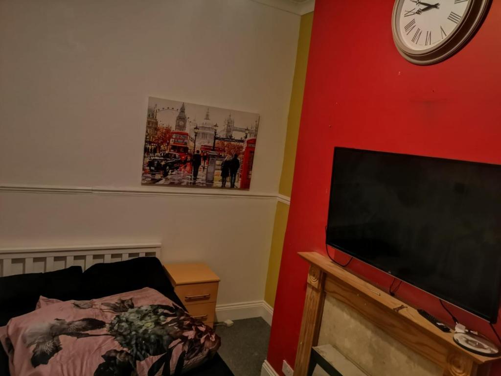 salon z telewizorem i zegarem na ścianie w obiekcie The Vacationers - Pvt Rooms with Shared Bath w mieście Sunderland