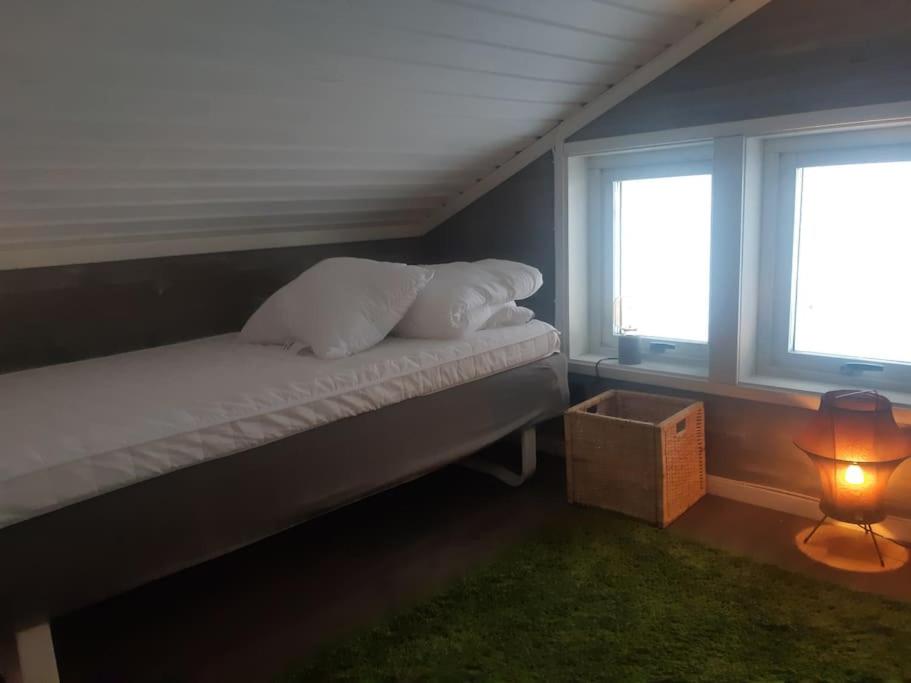 a bedroom with a bed with two windows and a lamp at Trollhålet 