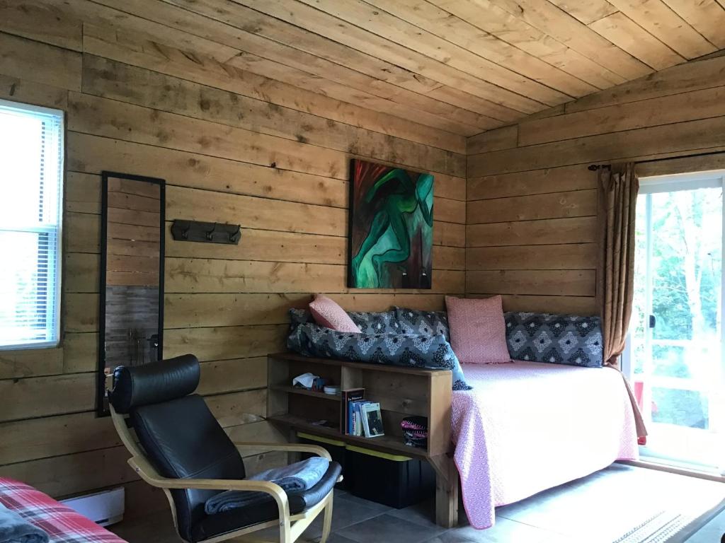 a bedroom with a bed and a chair at Loft Nature Laurentides in Val-des-Lacs