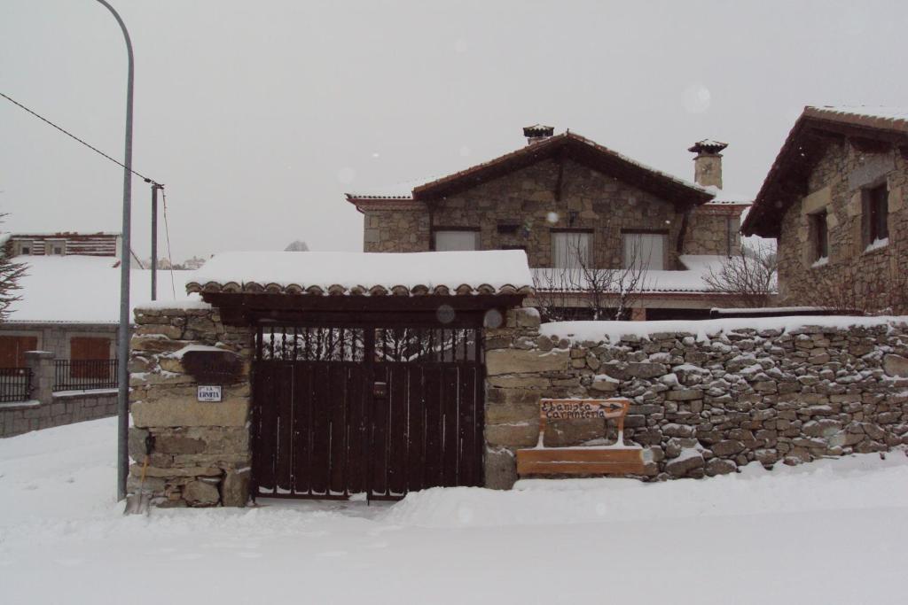 een stenen gebouw met een poort in de sneeuw bij Ermita de Gredos in Navarredonda de Gredos