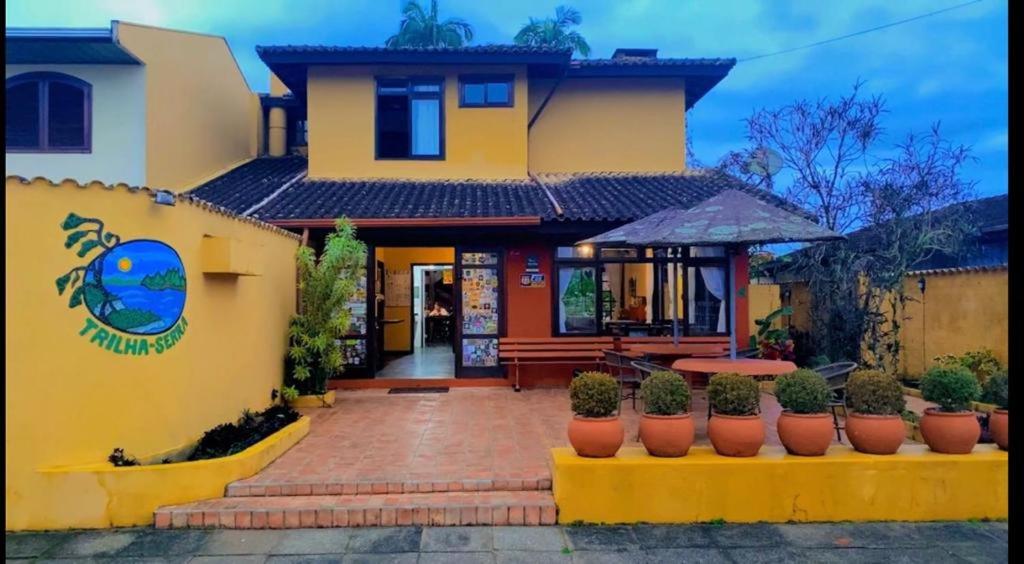 a yellow house with potted plants in front of it at Pousada Trilha da Serra in Morretes