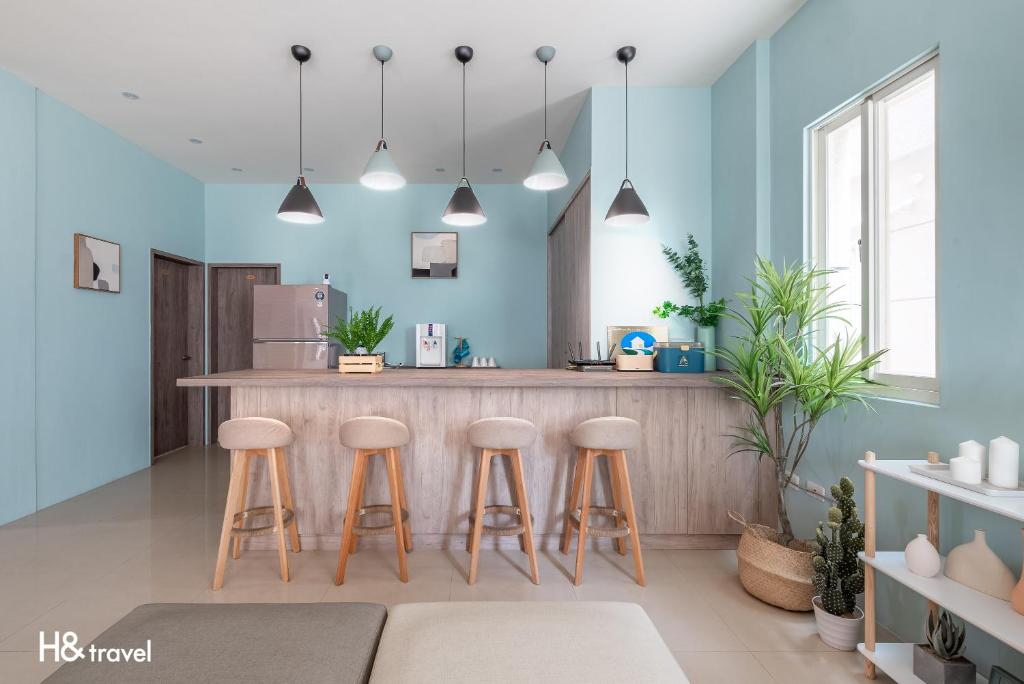 a kitchen with blue walls and a counter with stools at 澎湖芸庭旅店 l 全自助入住 in Magong