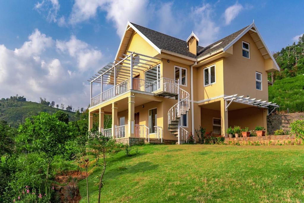 uma casa amarela numa colina com um quintal em Yellow Tulip with Breakfast, BBQ Grill & Pet Home by StayVista em Coonoor