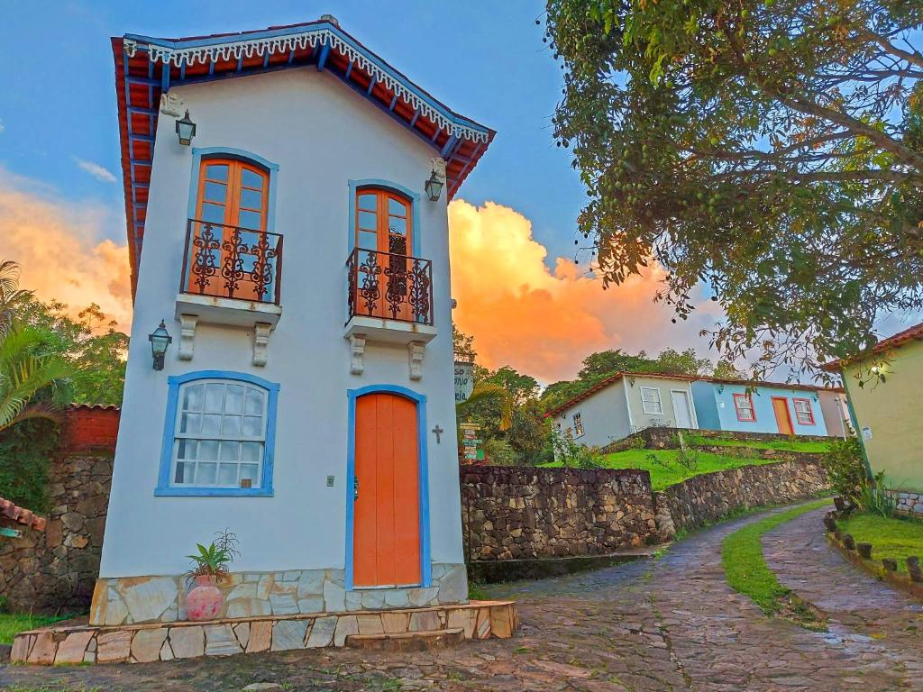 a white house with red doors and a fence at Pouso Antônio d'Maria in Tiradentes