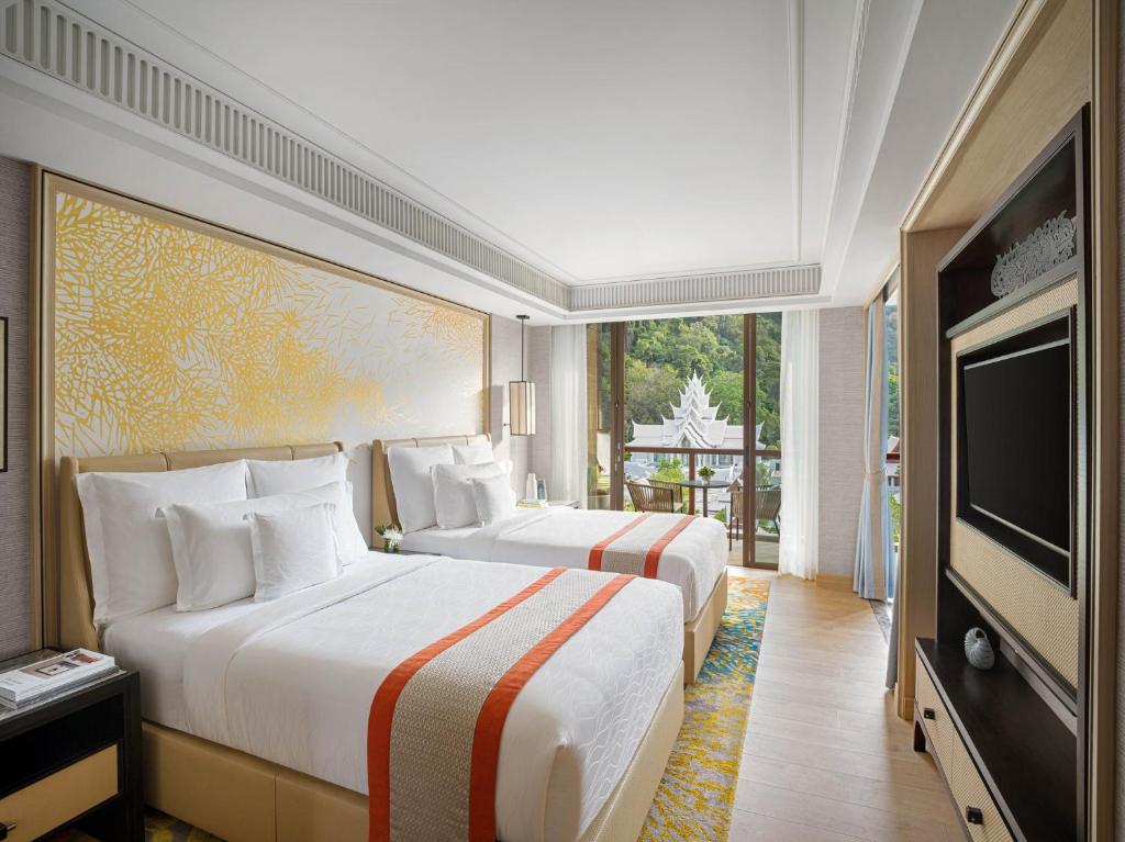 two beds in a room with a flat screen tv at InterContinental Phuket Resort by IHG in Kamala Beach
