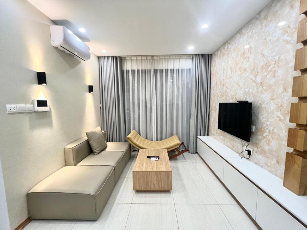 uma sala de estar com um sofá e uma televisão em vinhomes dcapitale 1 phòng ngủ em Hanói