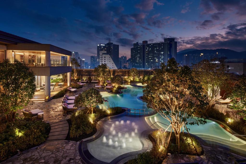 uma vista panorâmica de uma piscina numa cidade à noite em Lotte Hotel Busan em Busan