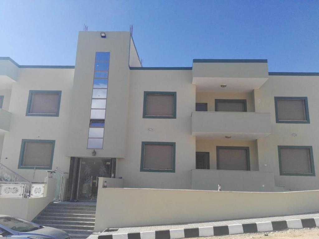 a white building with a car parked in front of it at noor apartment in Wadi Musa