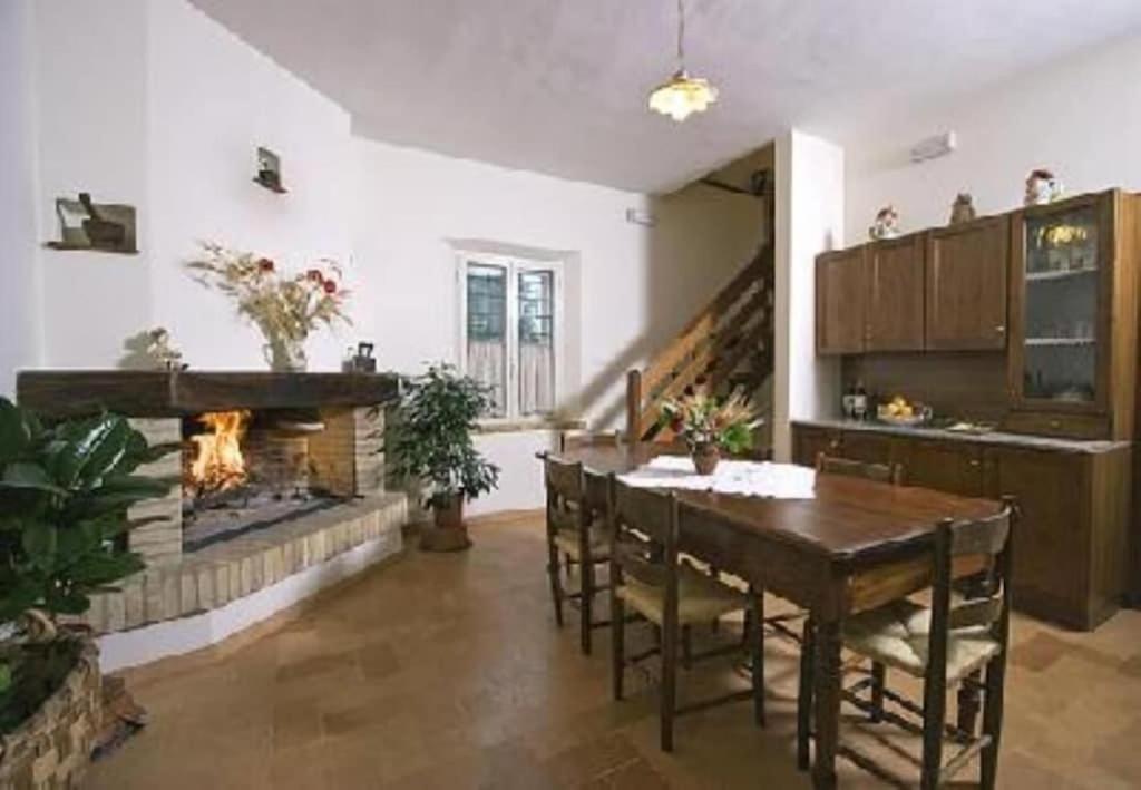 sala de estar con chimenea, mesa y sillas en Canalicchio Apartment Strategic for visiting Umbria, en Canalicchio