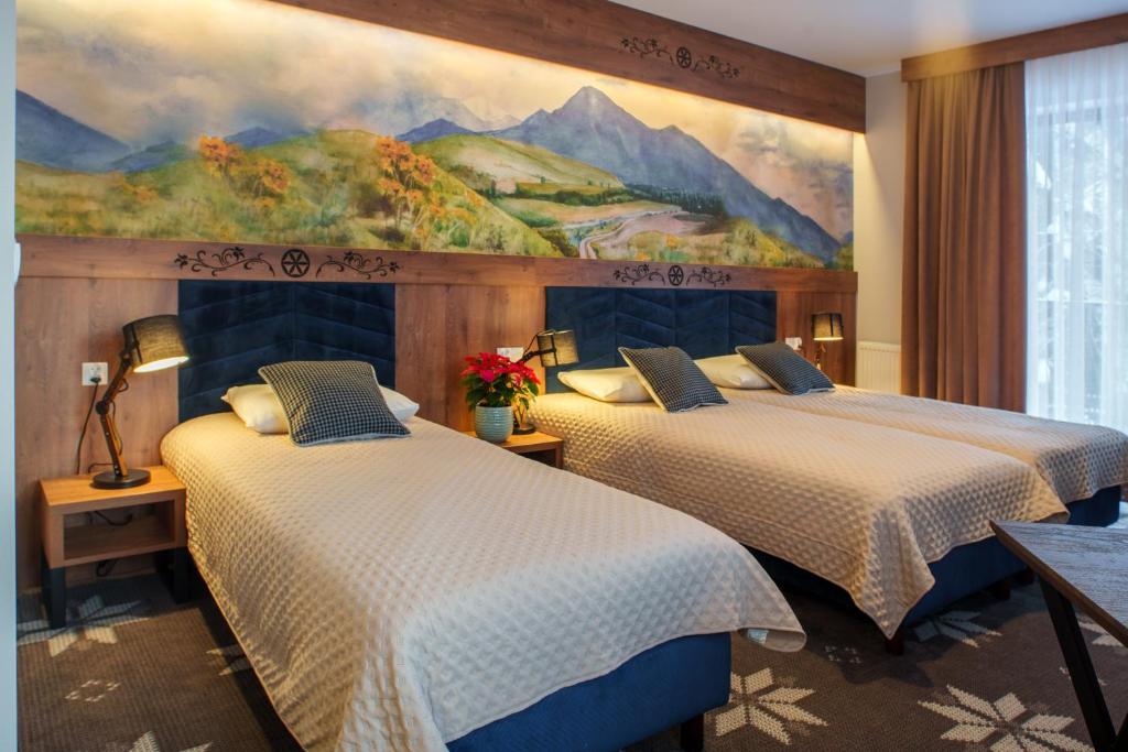 two beds in a hotel room with a painting on the wall at Willa Maria 4 in Zakopane