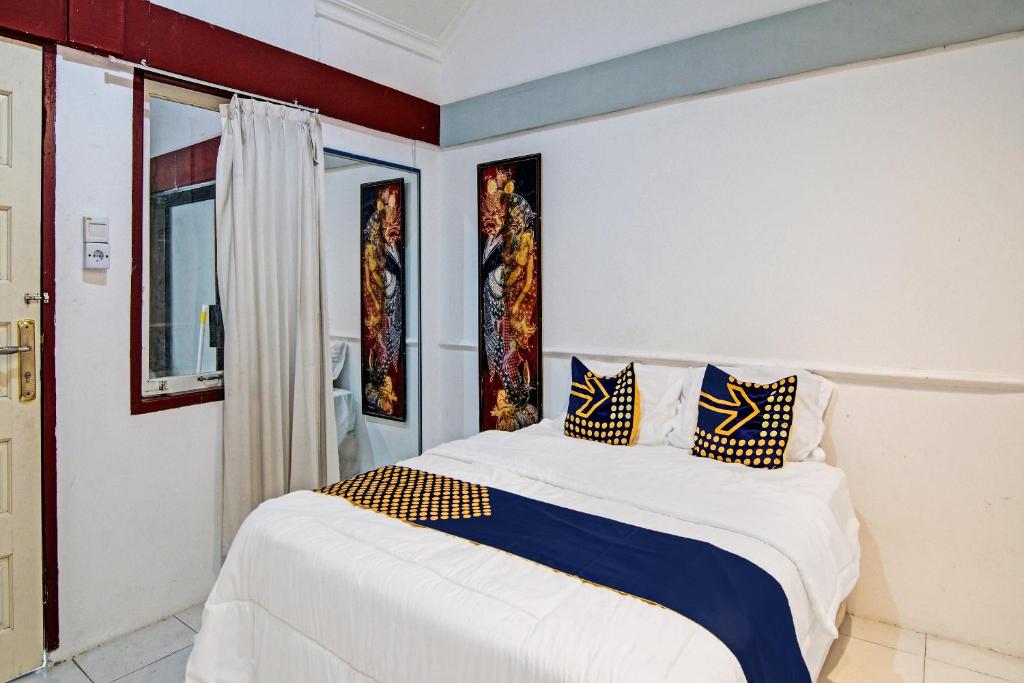 SPOT ON 92052 Aulya Homestay Syariah في Bangkinang: غرفة نوم مع سرير أبيض كبير مع لهجات زرقاء