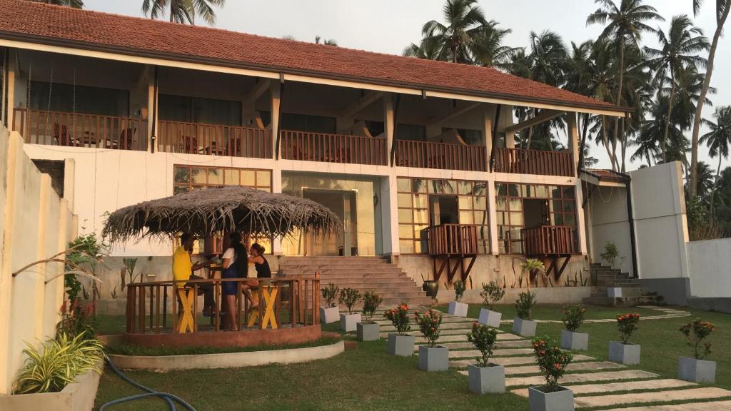 zwei Personen, die unter einem Schirm vor einem Gebäude stehen in der Unterkunft ISAMAR FRONT BEACH in Marawila