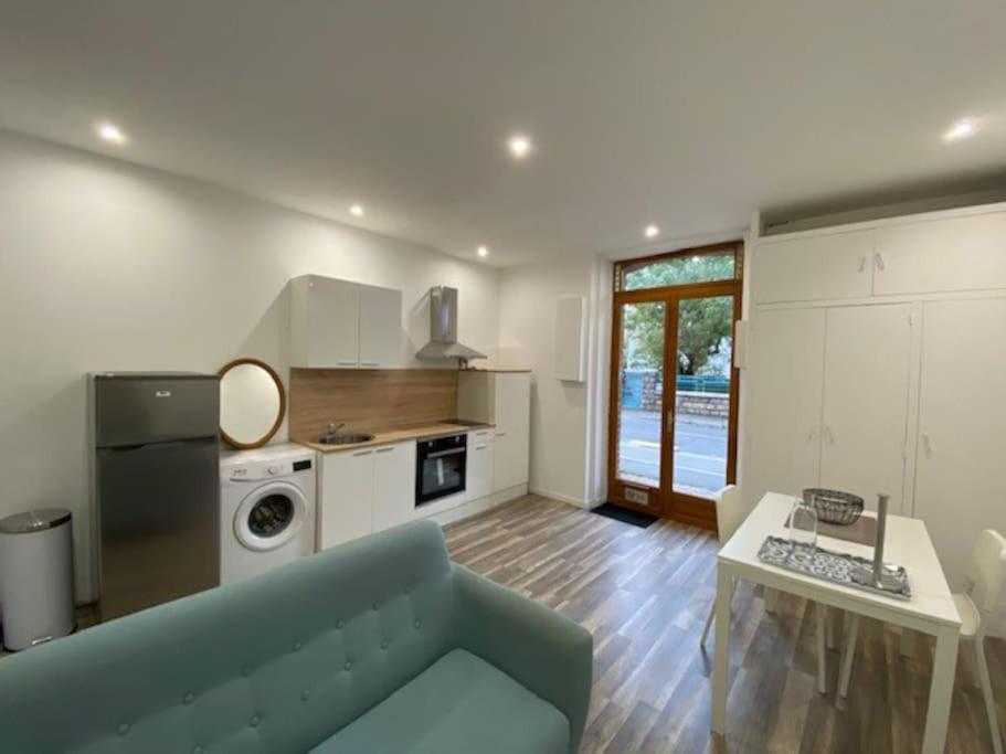ein Wohnzimmer mit einem blauen Sofa und einer Küche in der Unterkunft Le pasteur Charmant appartement tout confort in Unieux