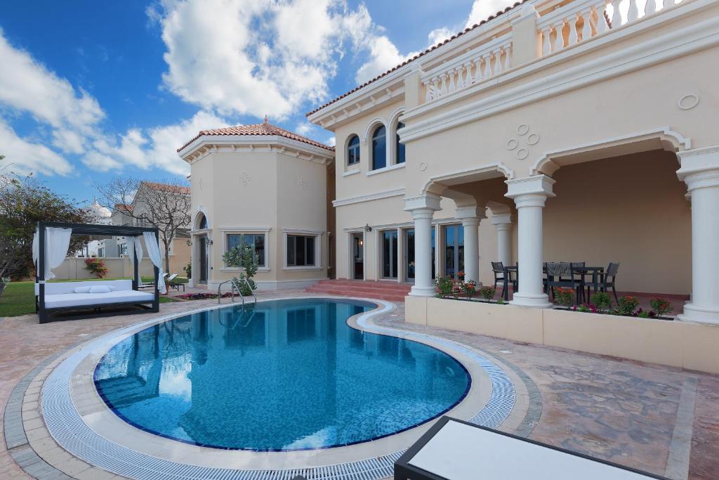 a swimming pool in front of a house at Maison Privee - Palm Jumeirah Beach Front XL Villa with Private Pool in Dubai