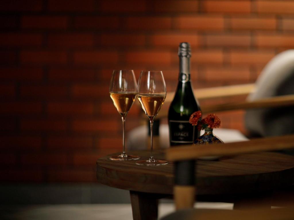 a table with two wine glasses and a bottle of wine at THE HOTEL SANRAKU KANAZAWA 21th December 2022 OPEN in Kanazawa