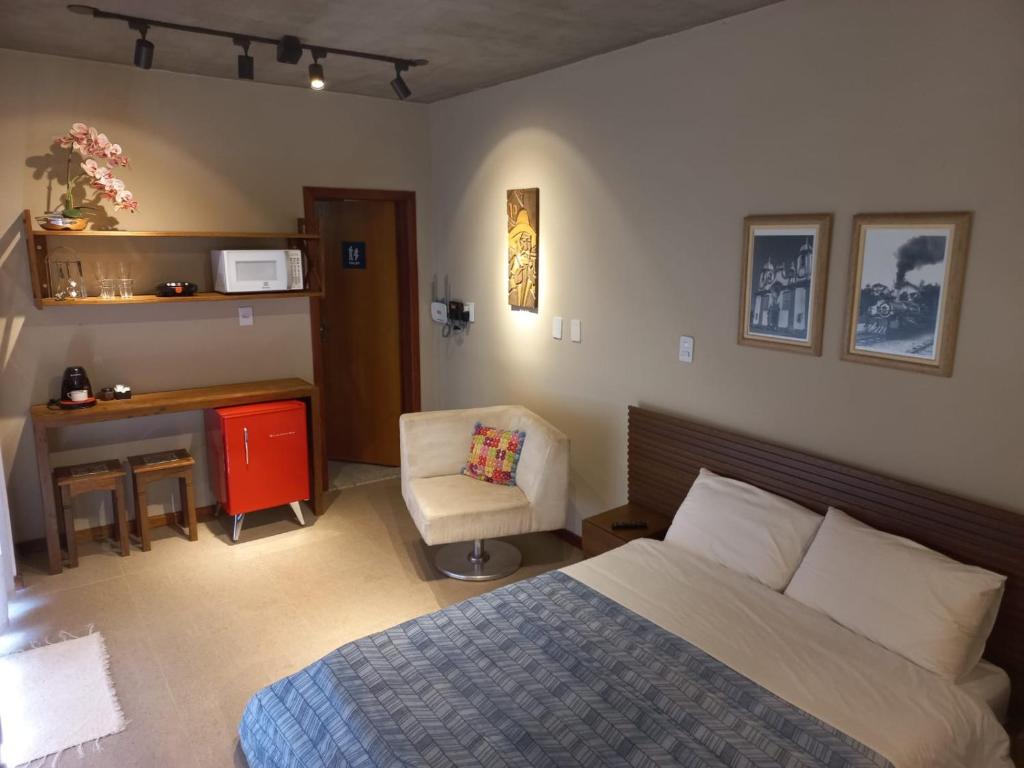 Schlafzimmer mit einem Bett, einem Schreibtisch und einem Stuhl in der Unterkunft Chalés Belo Vale - Tiradentes in Tiradentes