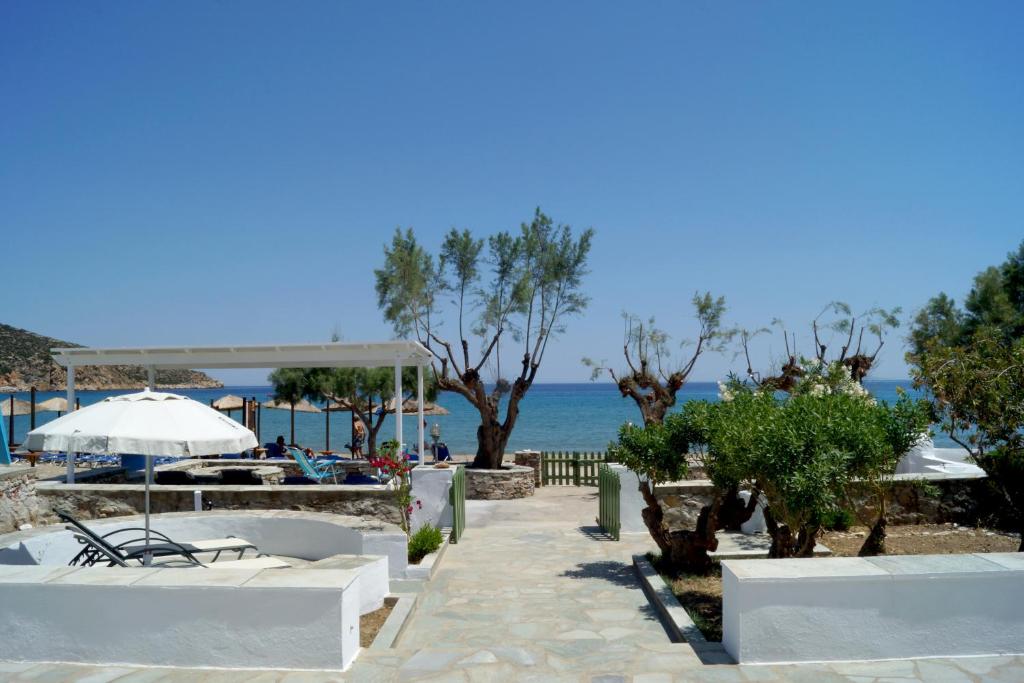 a beach with chairs and an umbrella and the ocean at LEANDROS APARTMENTS in Platis Gialos