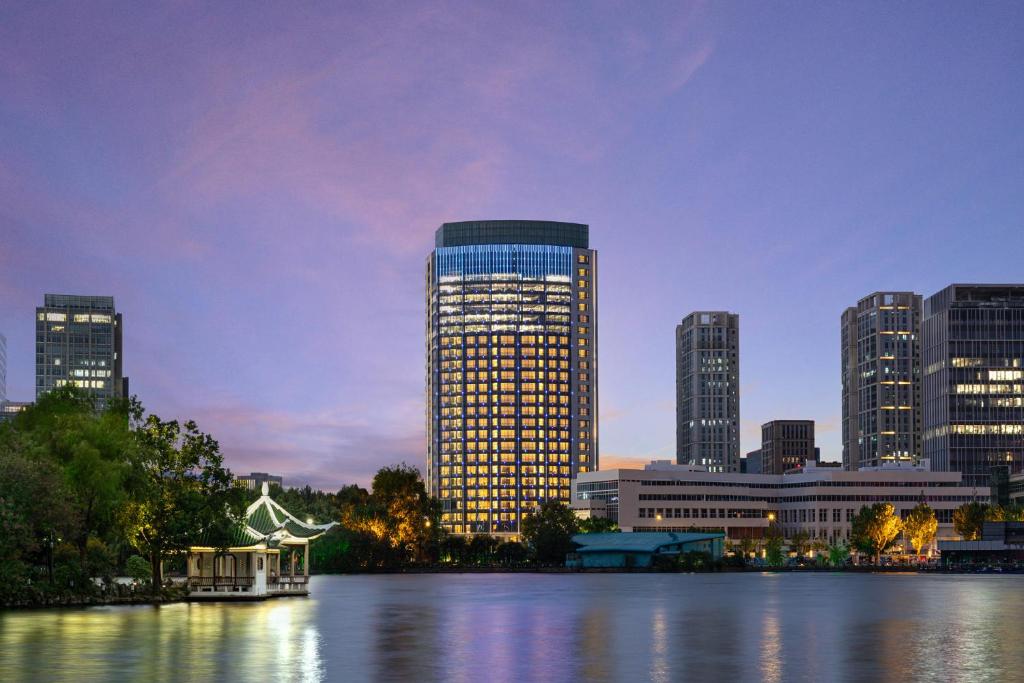 um grande edifício com luzes acesas numa cidade em HUALUXE Shanghai Changfeng Park, an IHG Hotel em Xangai