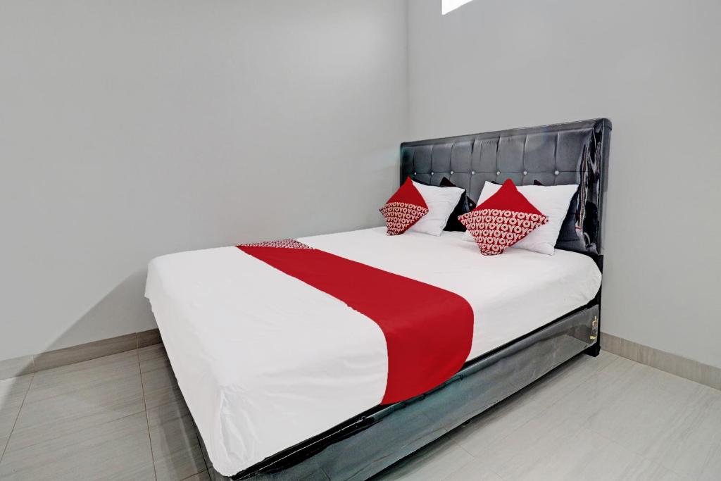 Cama con sábanas y almohadas rojas y blancas en OYO 92057 Reny Kost Syariah en Jambi