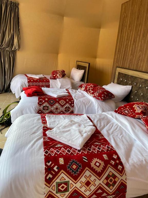 two beds with red and white blankets and pillows at Bronze Mountains Camp Wadi Rum in Wadi Rum