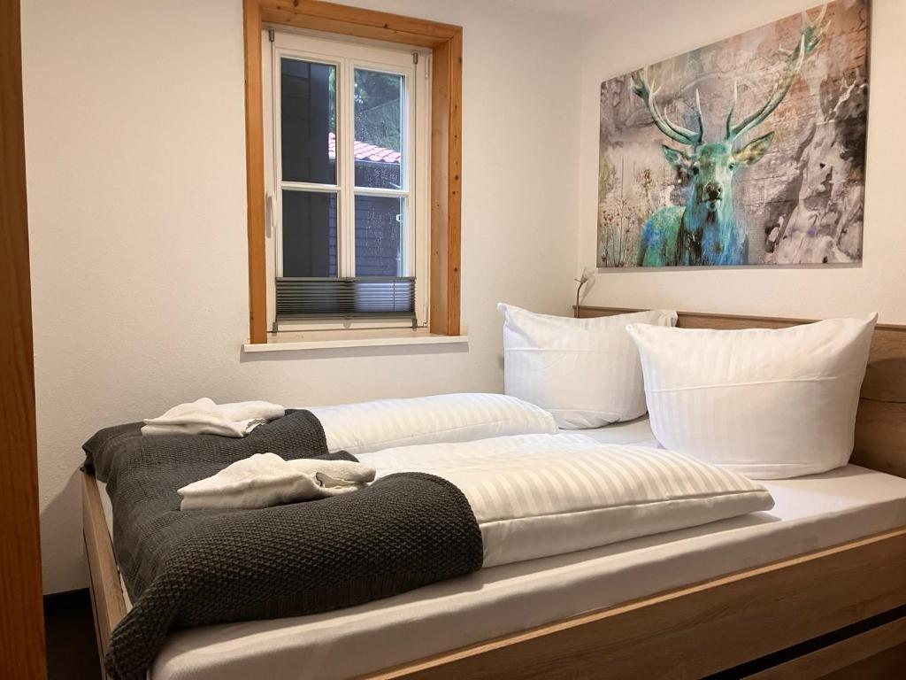 a bed with white pillows and a picture of a deer at Steinbachhütte 1 in Drei Annen Hohne