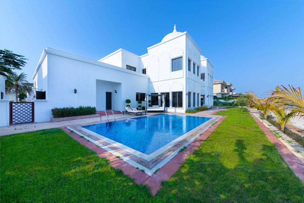 a villa with a swimming pool in front of a house at Maison Privee - 5 Stars Villa with Private Pool or Beach on Palm Jumeirah in Dubai
