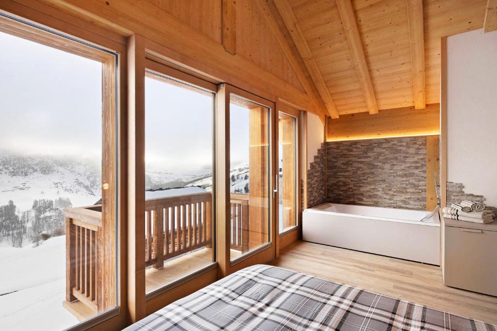 a bedroom with a bed and windows with a view at Plaz in Livigno