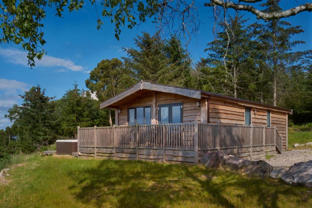 a cabin in the woods with a large deck at Burgie Woodland Lodges in Forres