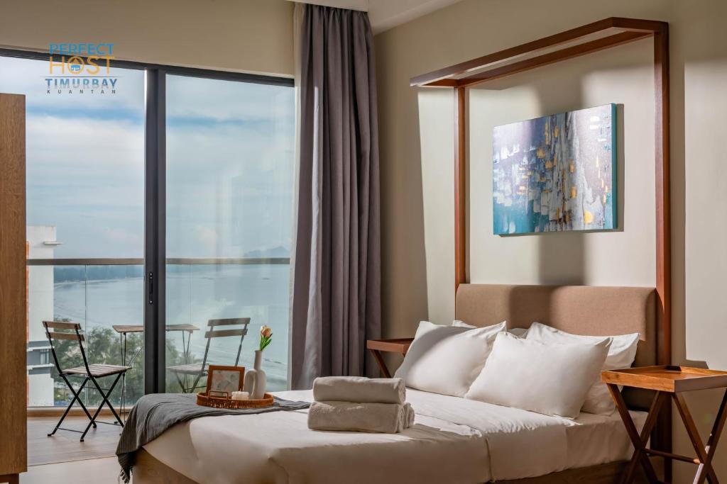 クアンタンにあるTimurbay Beachfront by Perfect Hostのベッドとバルコニー付きのホテルルーム
