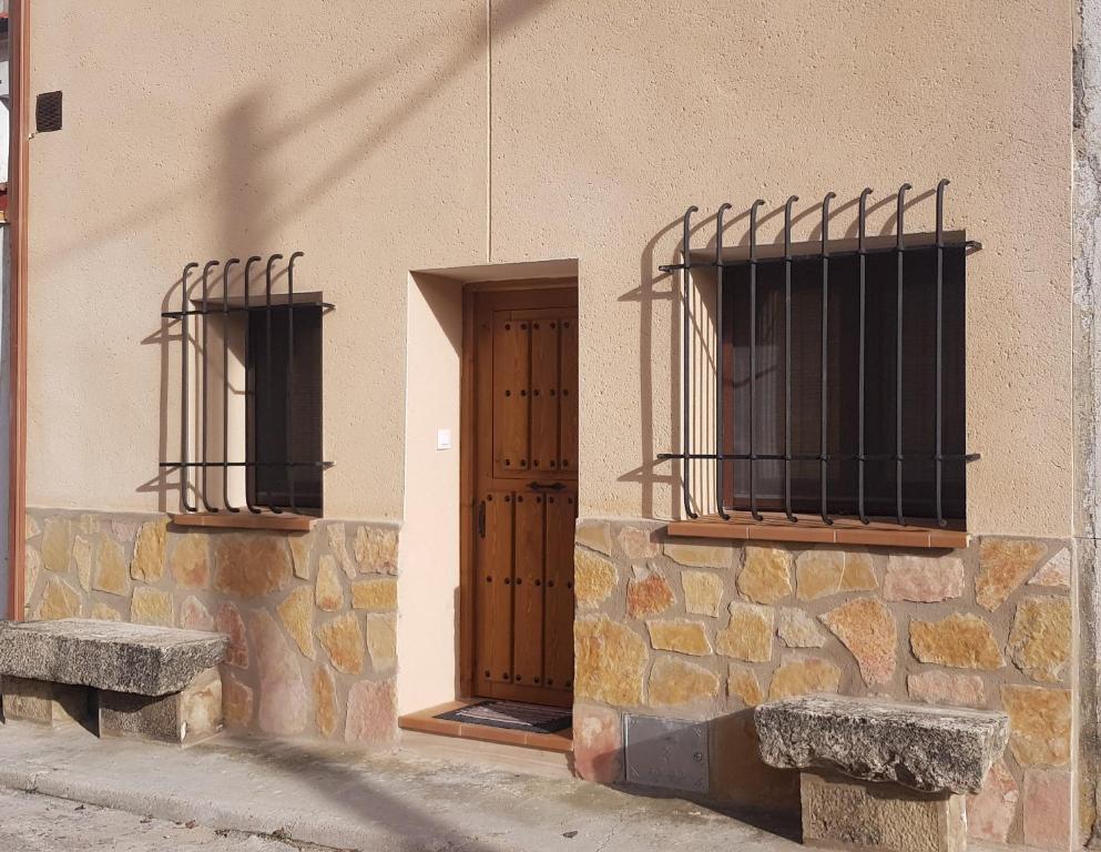 a building with two windows and a door and two benches at CASA La Playeta in Puente de Vadillos