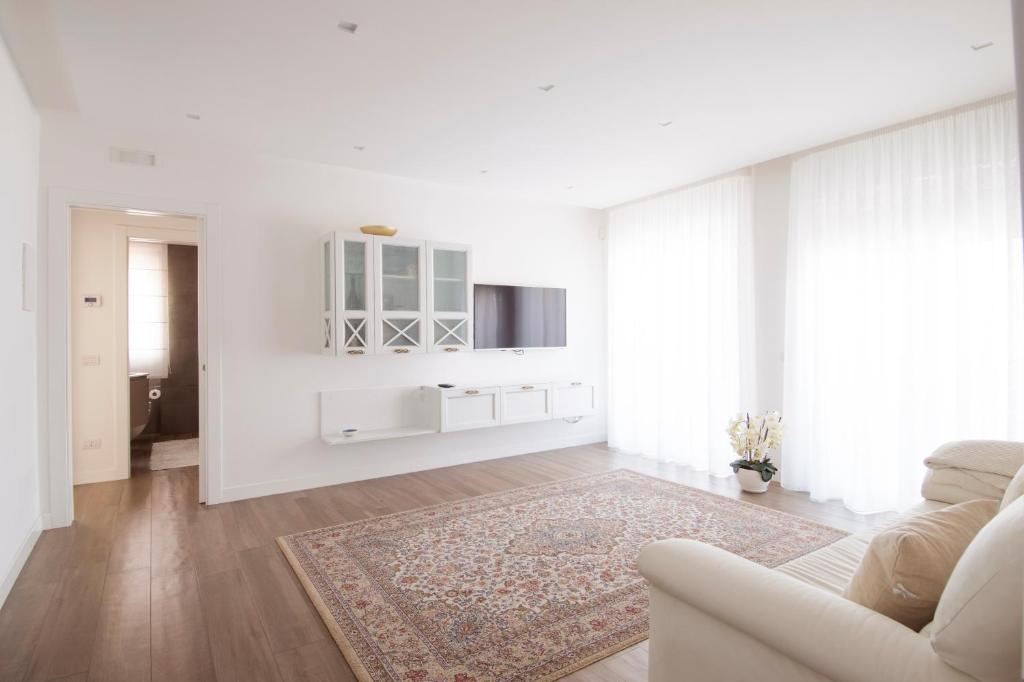 Sala de estar blanca con sofá y alfombra en Casa Armonia by MONHOLIDAY en Monopoli